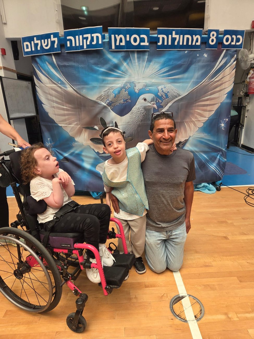 מר אייל עוזרי עם תלמידי הכנס מול באנר תקווה לשלום